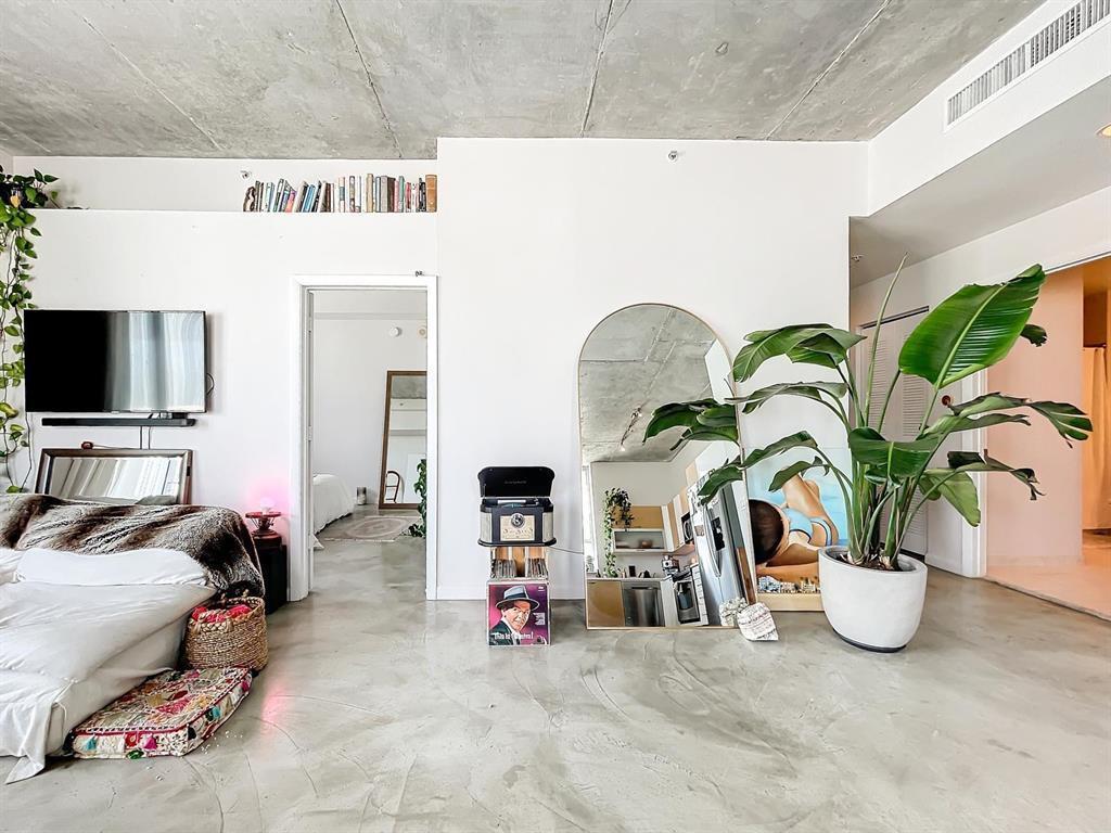 A living area with concrete floors and ceiling, a large arched mirror, and a potted plant — 234 NE 3rd Street # 1901, Miami FL 33132, MIAMI, FL
