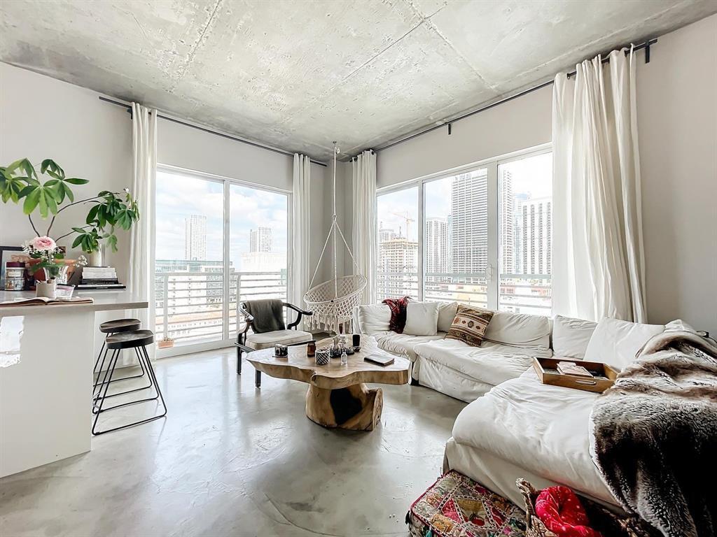 A modern living room features a concrete ceiling, white sofa, and a live-edge wood table — 234 NE 3rd Street # 1901, Miami FL 33132, MIAMI, FL