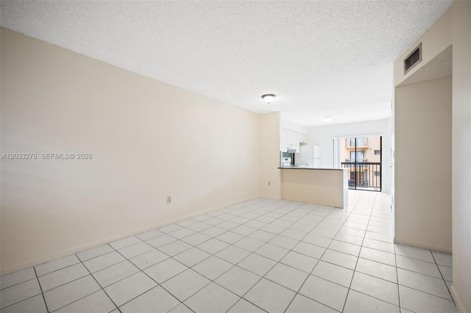 An open-concept living and dining area features white tile flooring and a kitchen pass-through — 5490 W 21st Ct # 310, Hialeah FL 33016, HIALEAH, FL