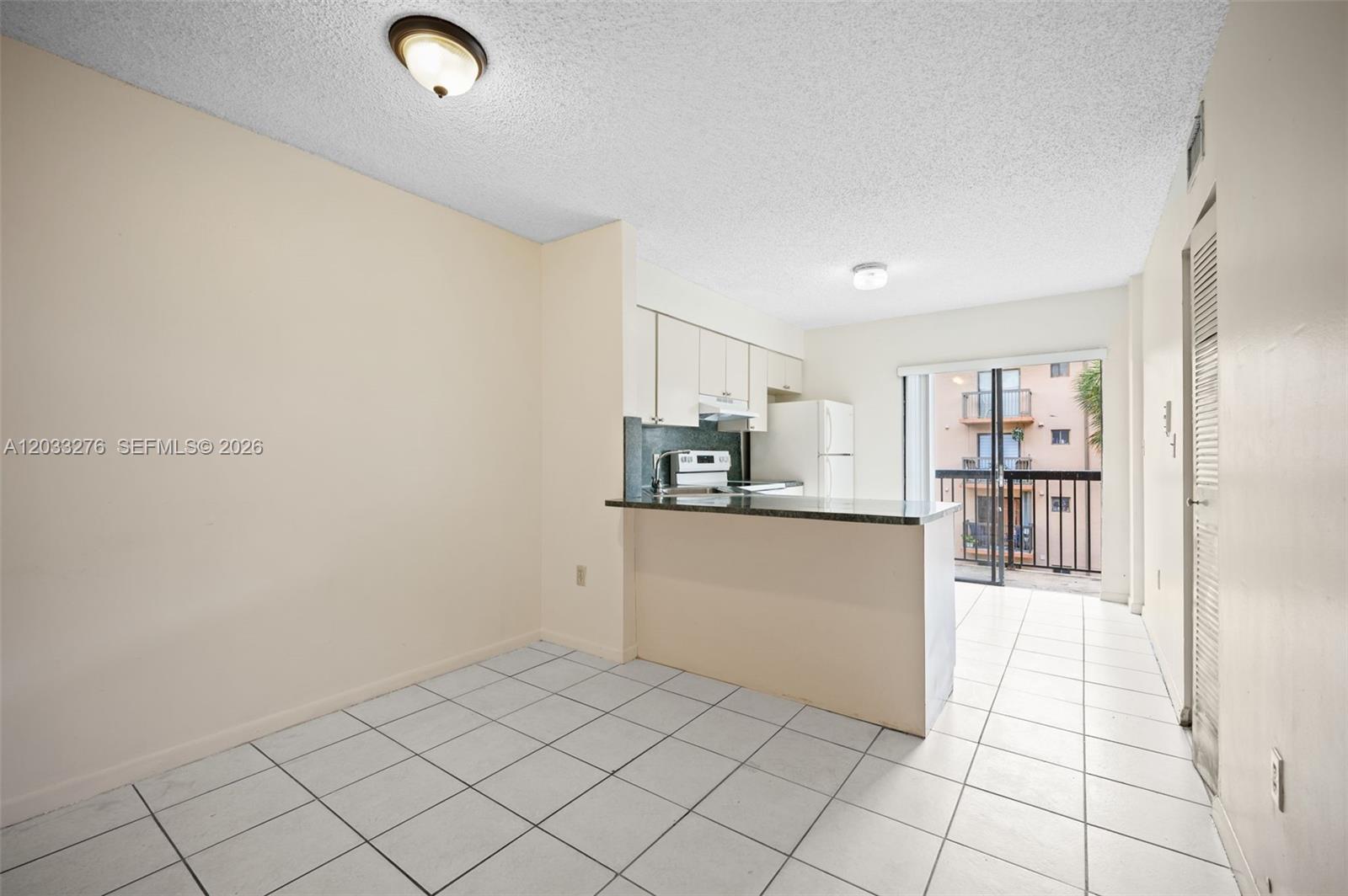 A kitchen with white cabinets and a breakfast bar opens to a balcony — 5490 W 21st Ct # 310, Hialeah FL 33016, HIALEAH, FL