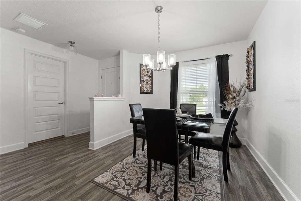 A dining room features a glass table, black chairs, a patterned rug, and a chandelier — 236 ELM COURT, KISSIMMEE, FL