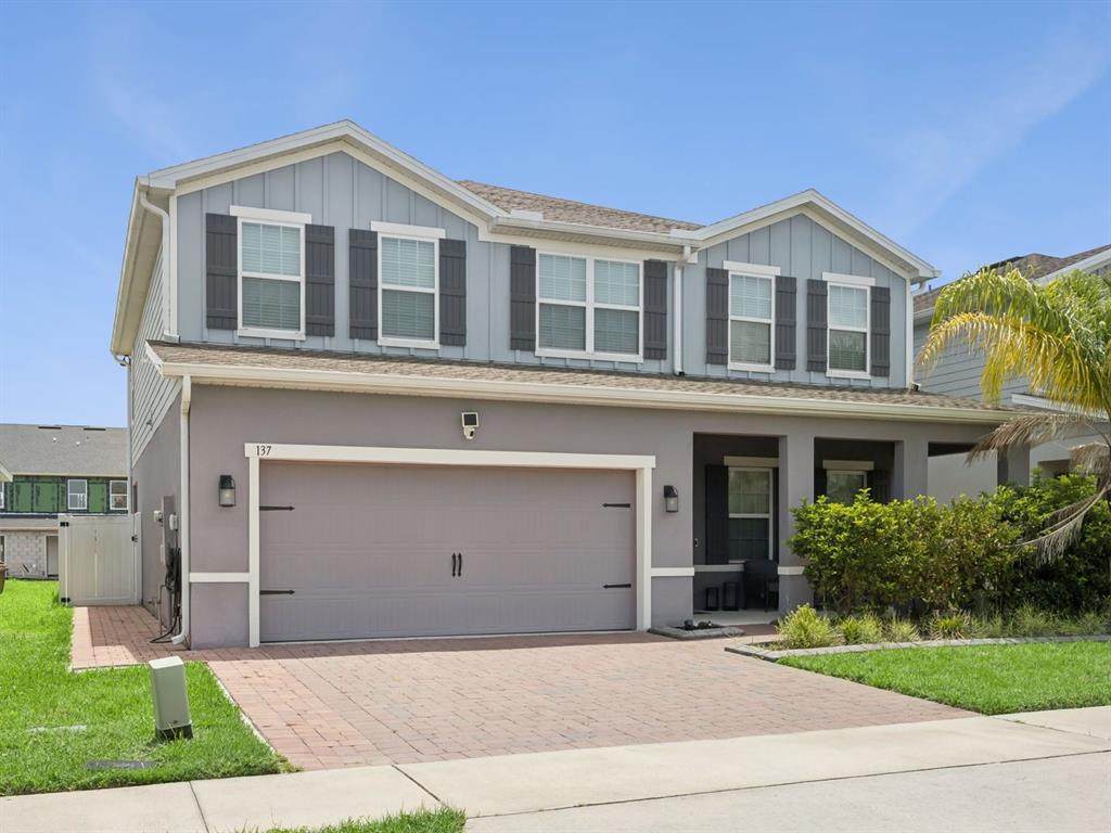 A two-story house with a gray stucco exterior, a two-car garage, and a paved driveway — 137 LAVENNA AVENUE, ST CLOUD, FL