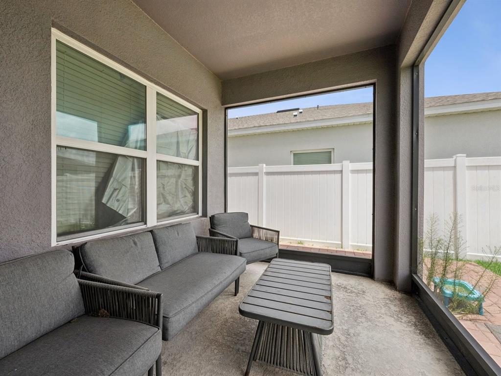 A covered patio features gray outdoor furniture, a coffee table, and a screened-in wall — 137 LAVENNA AVENUE, ST CLOUD, FL