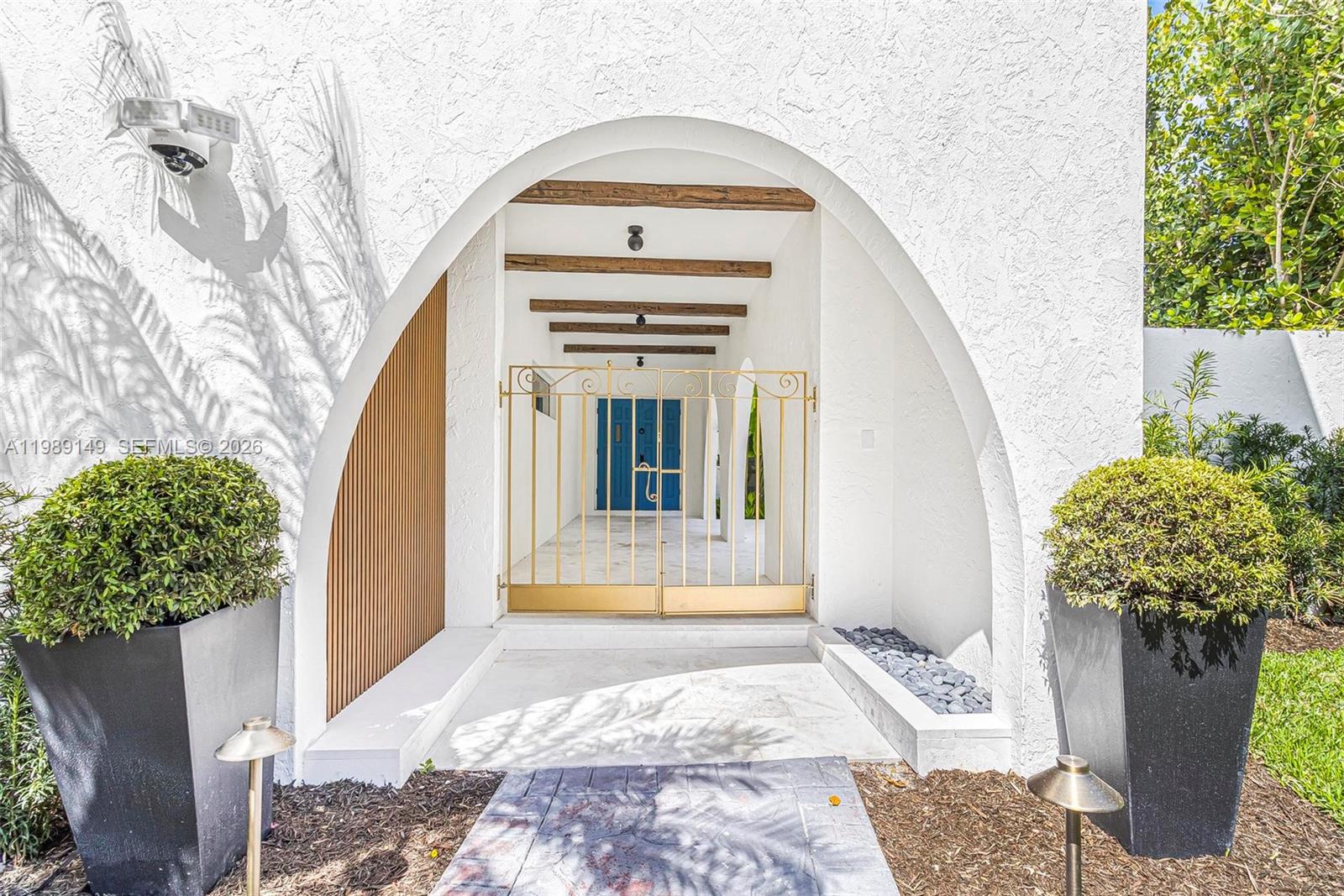 A white arched entryway features a gold metal gate, wooden ceiling beams, and planters — 18490 SW 83rd Pl, Cutler Bay FL 33157, CUTLER BAY, FL