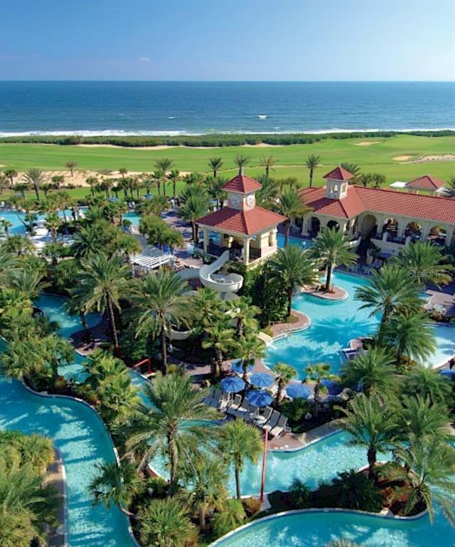 An aerial view shows a resort swimming pool complex with palm trees and ocean views — 52 OCEAN RIDGE BOULEVARD N, PALM COAST, FL
