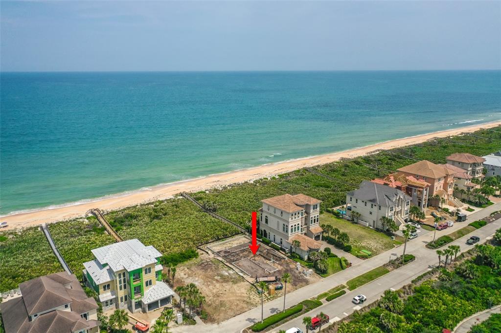 An aerial view shows a vacant beachfront lot with a foundation between two large houses — 52 OCEAN RIDGE BOULEVARD N, PALM COAST, FL