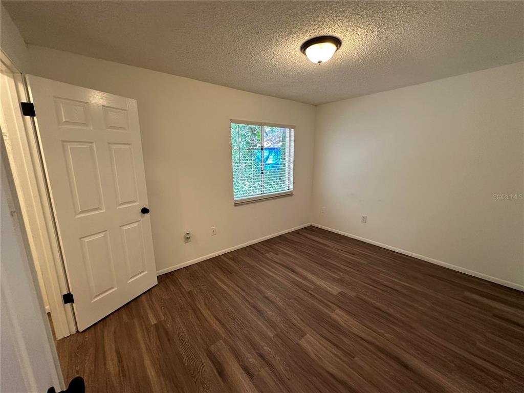 An empty bedroom features light-colored walls, a single window with blinds, and wood-look flooring — 1928 BONNEVILLE DRIVE, ORLANDO, FL