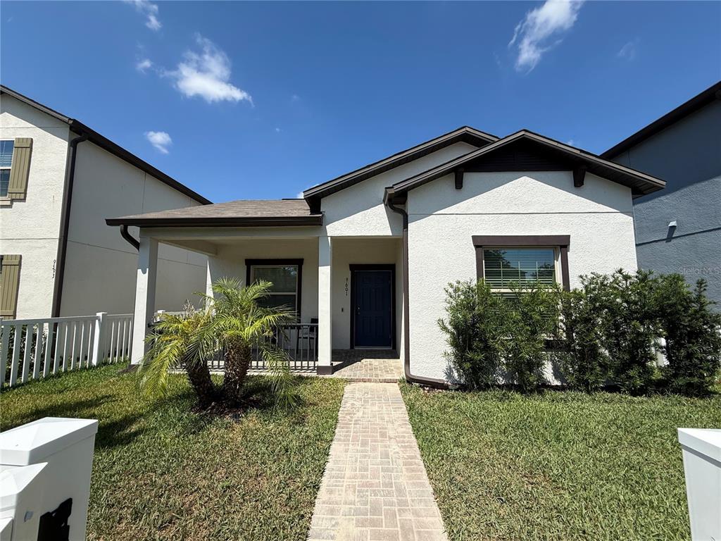 A single-story house with a white stucco facade, dark trim, and a brick paver walkway — 9601 FLOURISH DRIVE, LAND O LAKES, FL