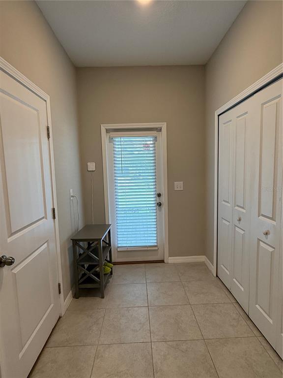 A tiled entryway features a door with blinds, a small gray shelf, and white doors — 9601 FLOURISH DRIVE, LAND O LAKES, FL