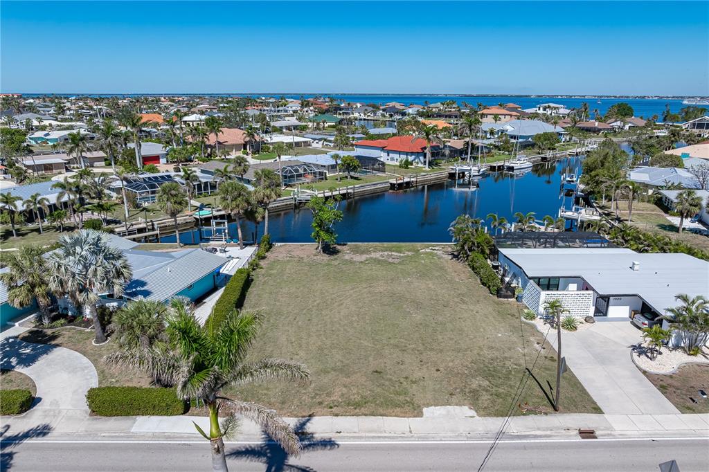 An aerial view shows a vacant waterfront lot situated between two residential houses — 1940 W MARION AVENUE, PUNTA GORDA, FL