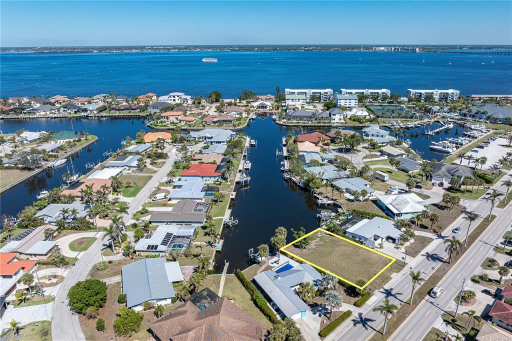 An aerial view shows a vacant waterfront lot highlighted in yellow near a canal — 1940 W MARION AVENUE, PUNTA GORDA, FL