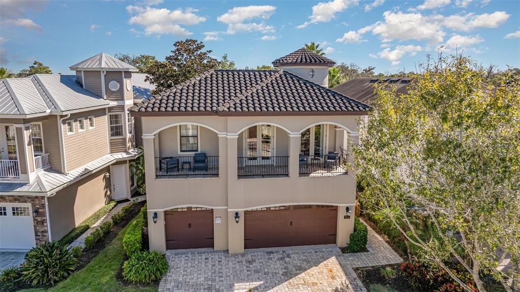 An aerial view of a two-story house with a balcony, tile roof, and garage doors — 1025 CASTLE PINES COURT, REUNION, FL