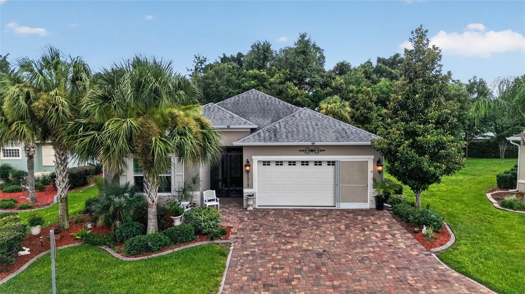 A single-story house with a brick paver driveway, a two-car garage, and surrounding landscaping — 10212 JULIA ISLES AVENUE, OXFORD, FL