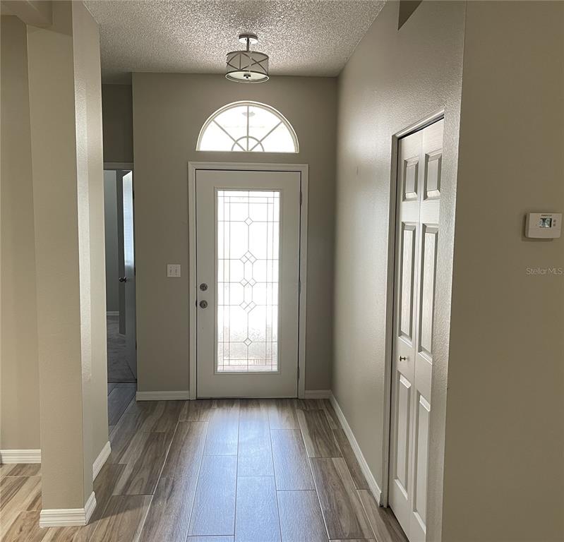 An entryway features wood-look tile flooring, a front door with a glass insert, and a closet — 2222 MAYFIELD PALMS LANE UNIT 322, SUN CITY CENTER, FL