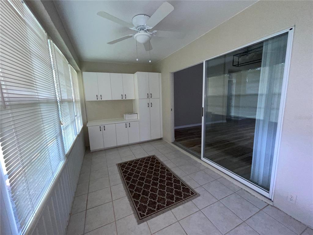 A sunroom features white cabinets, tile flooring, a ceiling fan, and sliding glass doors — 2222 MAYFIELD PALMS LANE UNIT 322, SUN CITY CENTER, FL