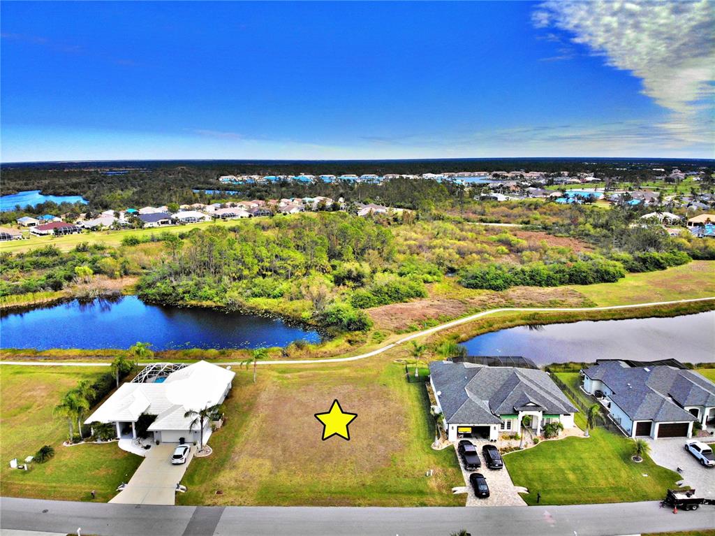 An aerial view shows a vacant residential lot situated between two houses near a pond — 12932 SW PEMBROKE CIRCLE S, LAKE SUZY, FL