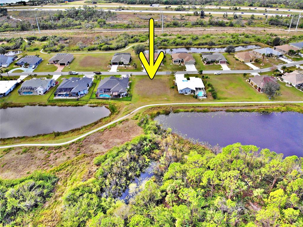 An aerial view shows a vacant residential lot situated between two houses near a pond — 12932 SW PEMBROKE CIRCLE S, LAKE SUZY, FL