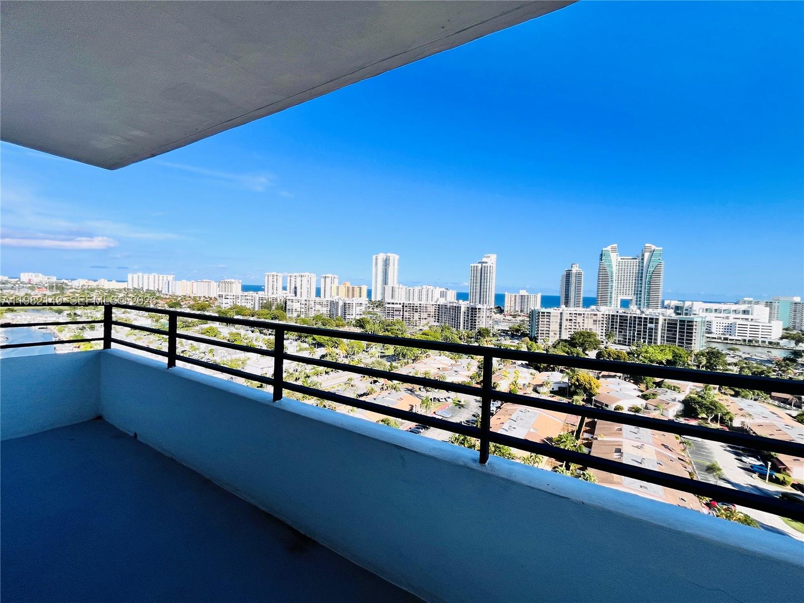 A balcony with a black metal railing overlooks a city skyline and the ocean — 2500 Parkview Dr # 1803, Hallandale Beach FL 33009, HALLANDALE BEACH, FL