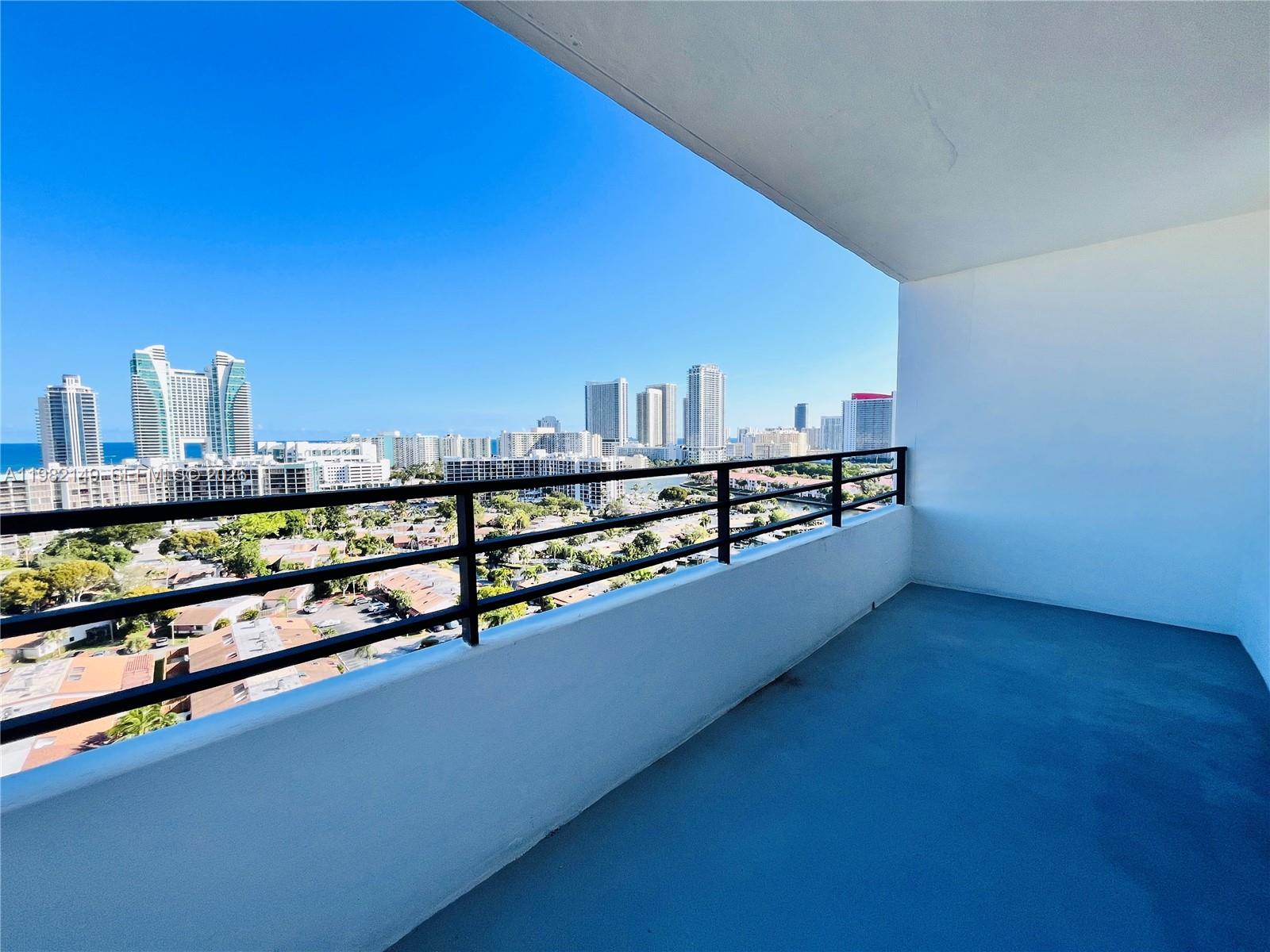 A high-rise balcony with a metal railing overlooks a city skyline and the ocean — 2500 Parkview Dr # 1803, Hallandale Beach FL 33009, HALLANDALE BEACH, FL