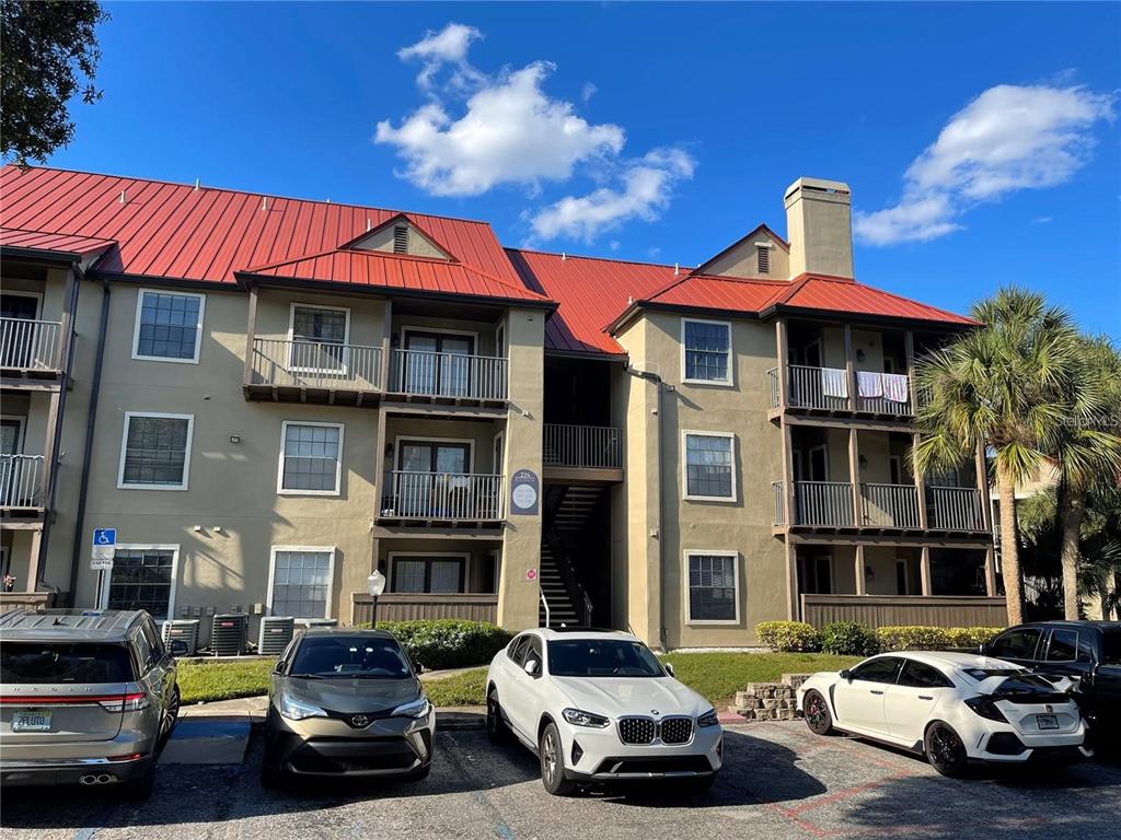 A multi-story apartment building with a red metal roof and parking spaces in front — 199 AFTON SQUARE UNIT 308, ALTAMONTE SPRINGS, FL