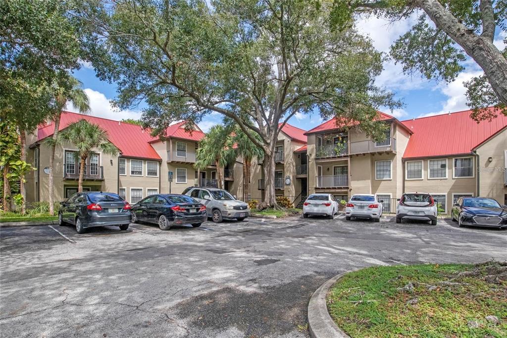 A multi-story apartment building with a red metal roof and a parking lot in front — 199 AFTON SQUARE UNIT 308, ALTAMONTE SPRINGS, FL