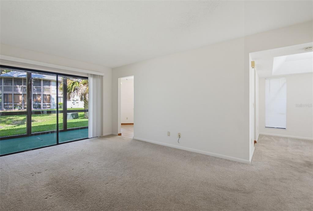 A carpeted living room features a sliding glass door leading to a screened-in patio — 7 MID PINES CIRCLE, PALM COAST, FL