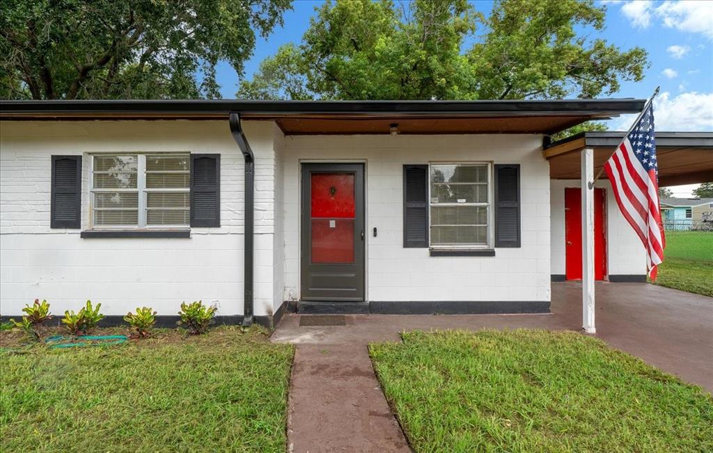 A white painted brick house with a front door, windows with shutters, and an American flag — 1708 E OHIO STREET, PLANT CITY, FL