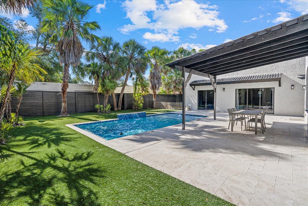 A backyard features a swimming pool with a water feature, a patio, and palm trees — 1185 S SHADE AVENUE, SARASOTA, FL