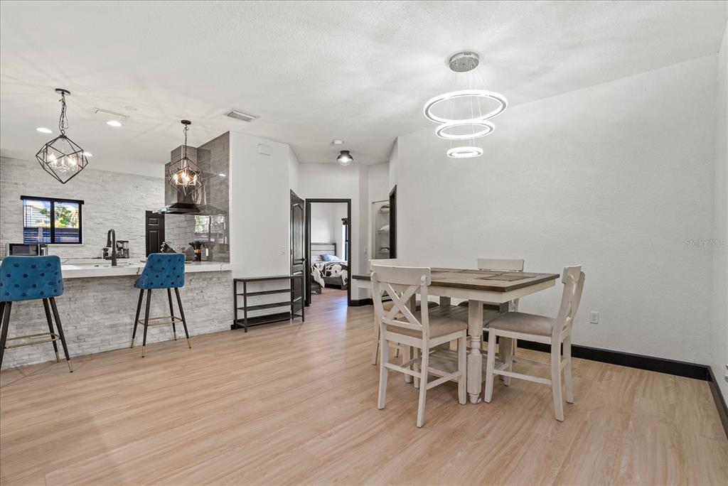 A dining area with a modern chandelier sits adjacent to a kitchen with bar seating — 1185 S SHADE AVENUE, SARASOTA, FL
