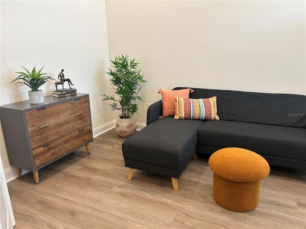 A living room features a dark gray sectional sofa, a wooden dresser, and a textured ottoman — 3630 SW 118TH DRIVE, GAINESVILLE, FL