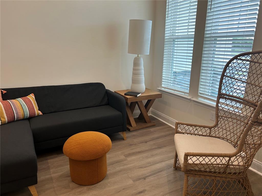 A living room features a dark sofa, a wooden side table, and a wicker chair — 3630 SW 118TH DRIVE, GAINESVILLE, FL