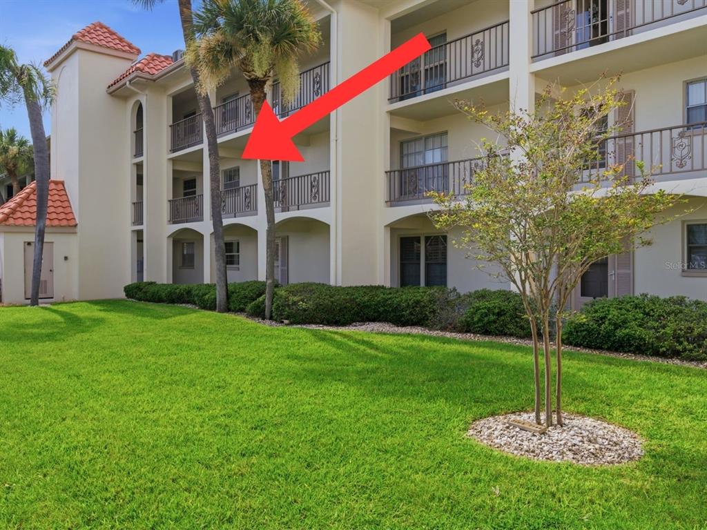 A red arrow points to the second-floor balcony of a multi-story apartment building — 19029 US HIGHWAY 19 N UNIT 7-12, CLEARWATER, FL