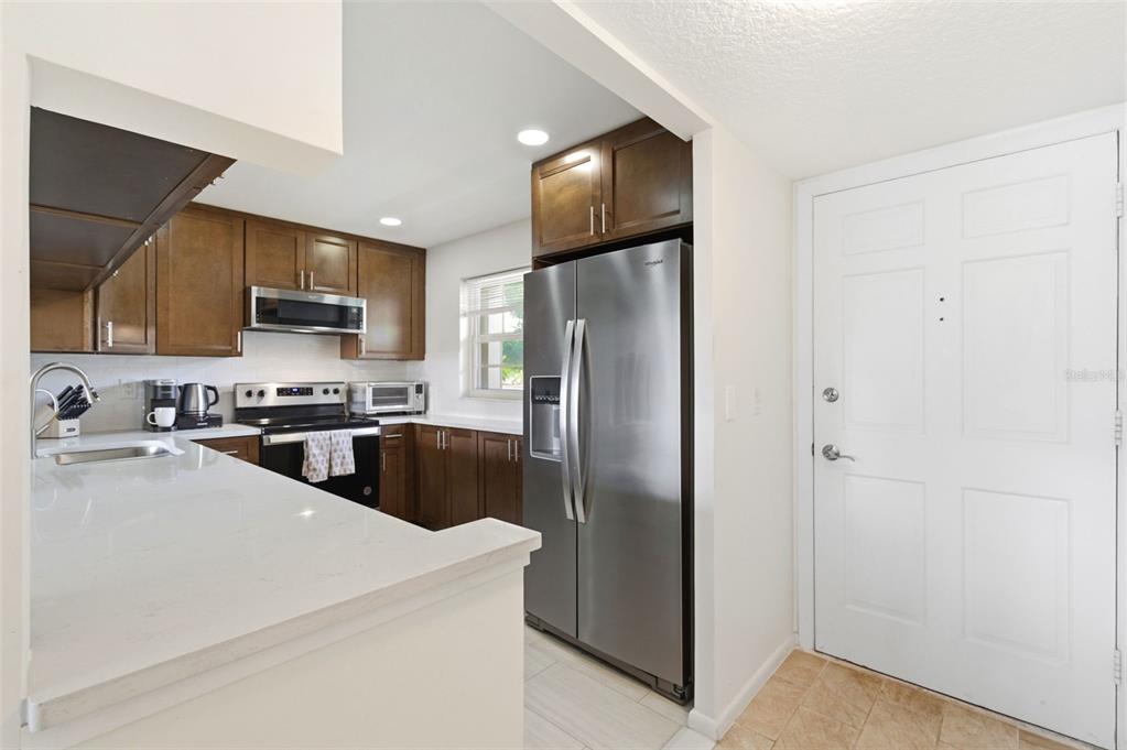 A kitchen with dark wood cabinets, stainless steel appliances, and a white quartz countertop — 19029 US HIGHWAY 19 N UNIT 7-12, CLEARWATER, FL