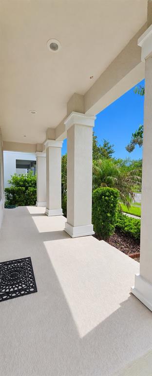 A covered porch features beige stucco columns and a textured concrete floor — 12156 PHILOSOPHY WAY, ORLANDO, FL