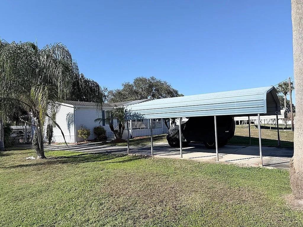 A white mobile home features a metal carport sheltering a vehicle on a grassy lot — 2086 STARBOARD DRIVE, GENEVA, FL