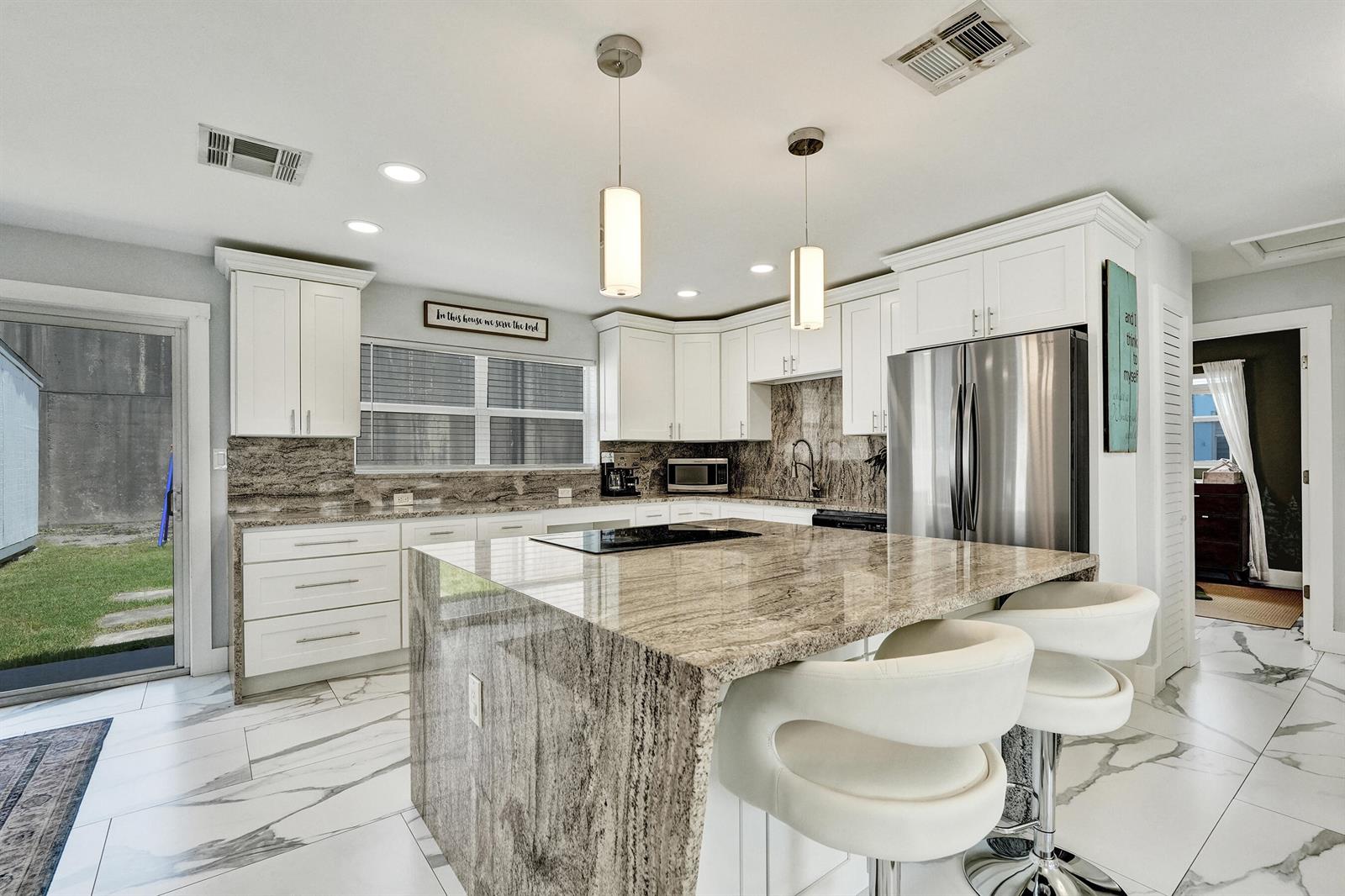 A kitchen features white cabinets, granite countertops, a large island, and white marble-patterned tile floors — 9446 Birmingham Drive, Palm Beach Gardens FL 33410, PALM BEACH GARDENS, FL