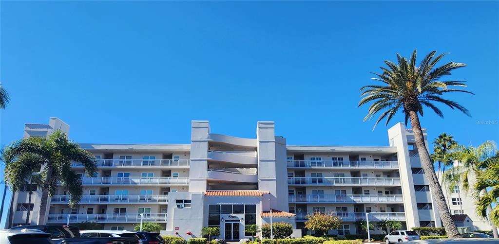 A multi-story apartment building with white balconies and palm trees under a clear blue sky — 5901 BAHIA DEL MAR CIRCLE UNIT 124, ST PETERSBURG, FL