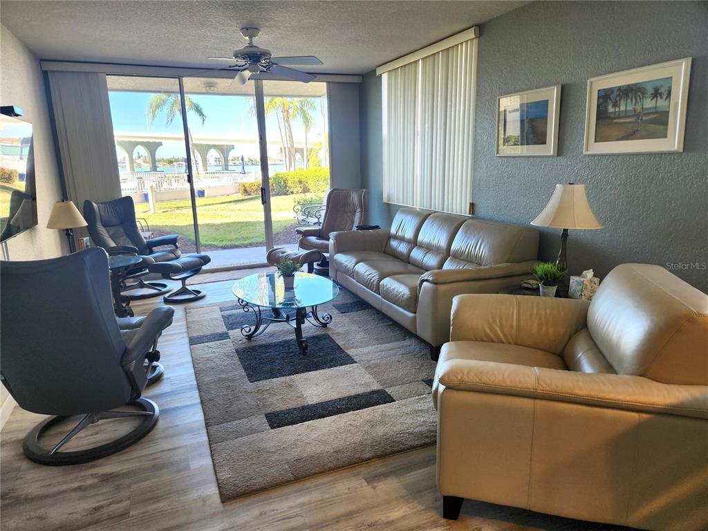 A living room features leather furniture, a glass coffee table, and a view of water — 5901 BAHIA DEL MAR CIRCLE UNIT 124, ST PETERSBURG, FL