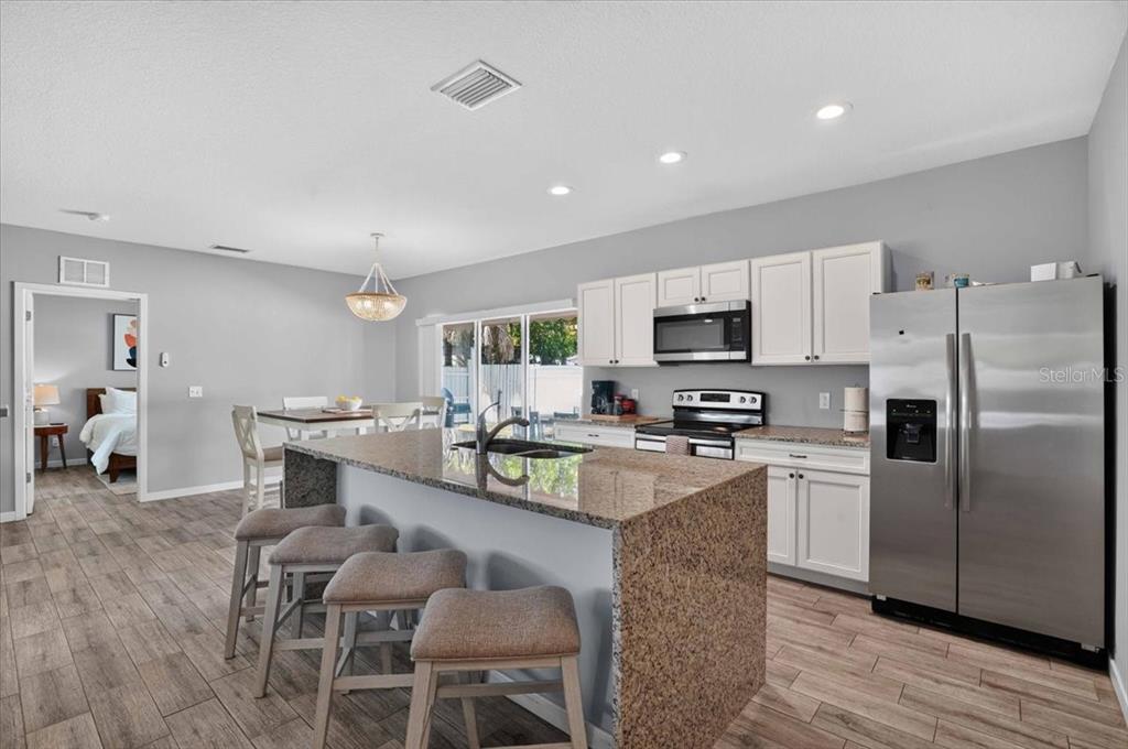 A kitchen with a granite-topped island, white cabinets, stainless steel appliances, and wood-look flooring — 2011 OUTER DRIVE UNIT 1, SARASOTA, FL