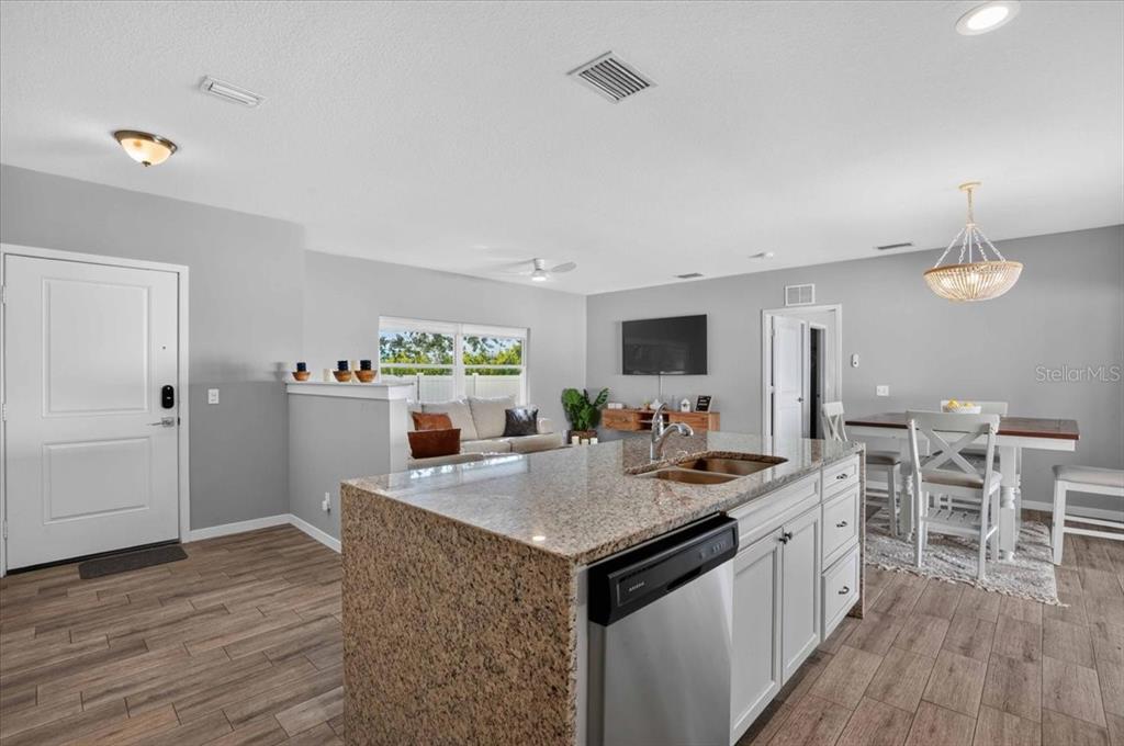 An open-concept kitchen with a granite island overlooks a living area and dining space — 2011 OUTER DRIVE UNIT 1, SARASOTA, FL