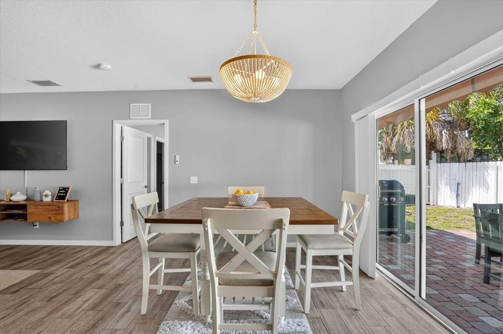 A dining area features a wooden table, white chairs, and a beaded chandelier on gray flooring — 2011 OUTER DRIVE UNIT 1, SARASOTA, FL