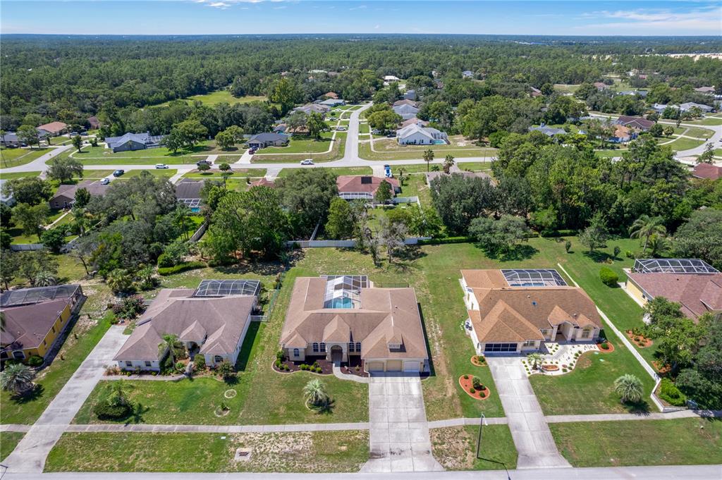 An aerial view of three suburban houses with swimming pools and driveways in a residential neighborhood — 6132 KRISTA DRIVE, SPRING HILL, FL