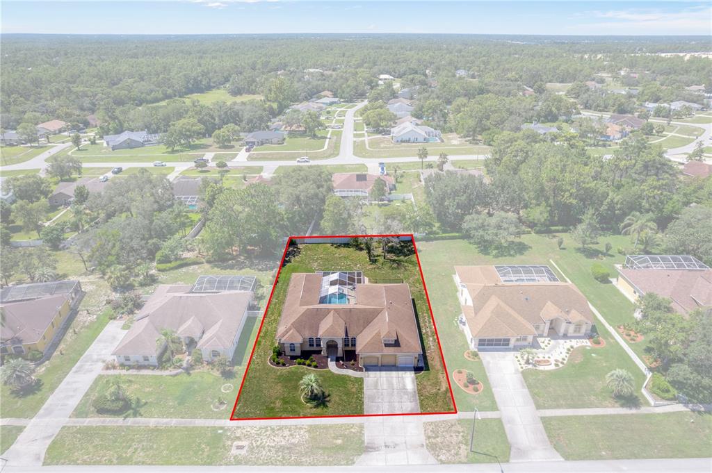 An aerial view shows a single-story house with a pool enclosure on a suburban lot — 6132 KRISTA DRIVE, SPRING HILL, FL