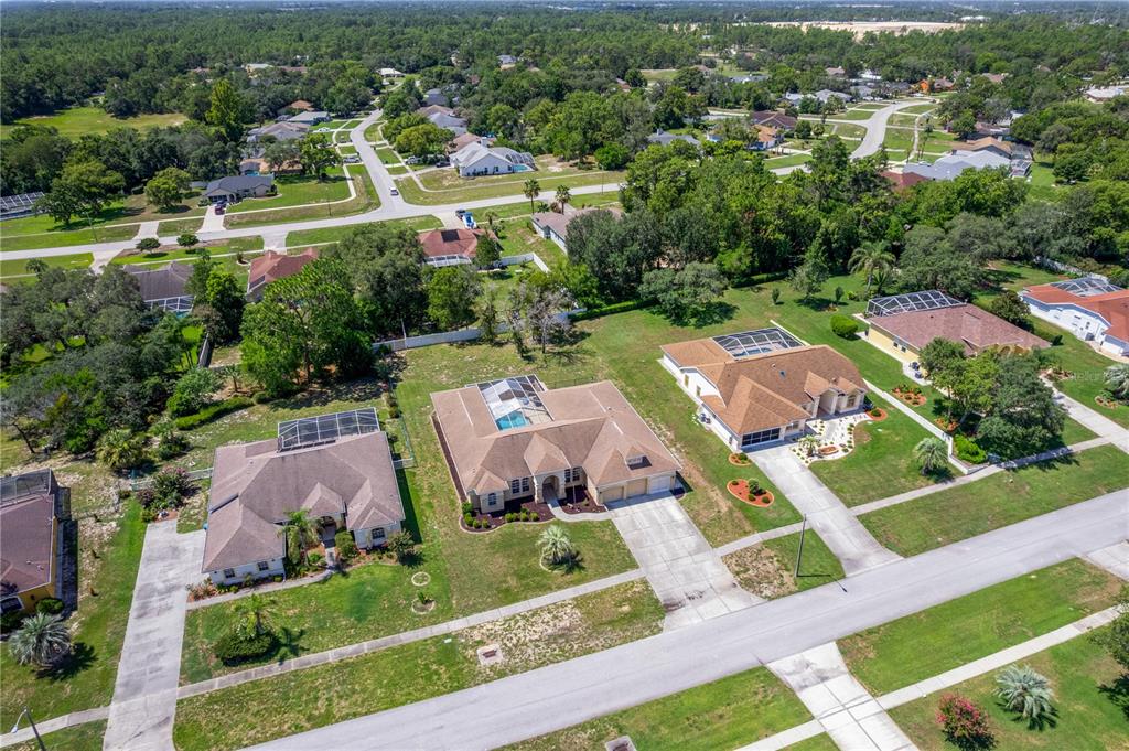 An aerial view shows three suburban houses with swimming pools and driveways along a street — 6132 KRISTA DRIVE, SPRING HILL, FL
