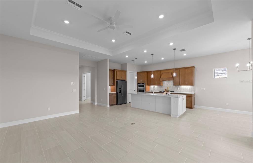 A spacious open-concept kitchen features a white island, wooden cabinetry, and light tile flooring — 1835 SILVER SHORES BOULEVARD, ENGLEWOOD, FL
