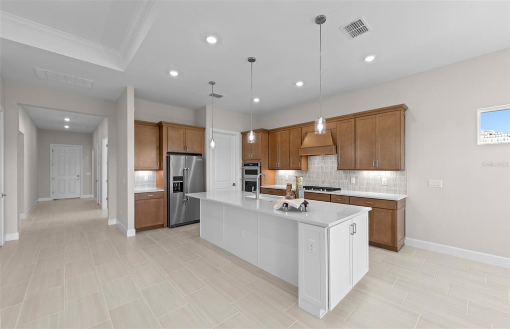 A kitchen features a white island, wooden cabinets, stainless steel appliances, and light tile flooring — 1835 SILVER SHORES BOULEVARD, ENGLEWOOD, FL