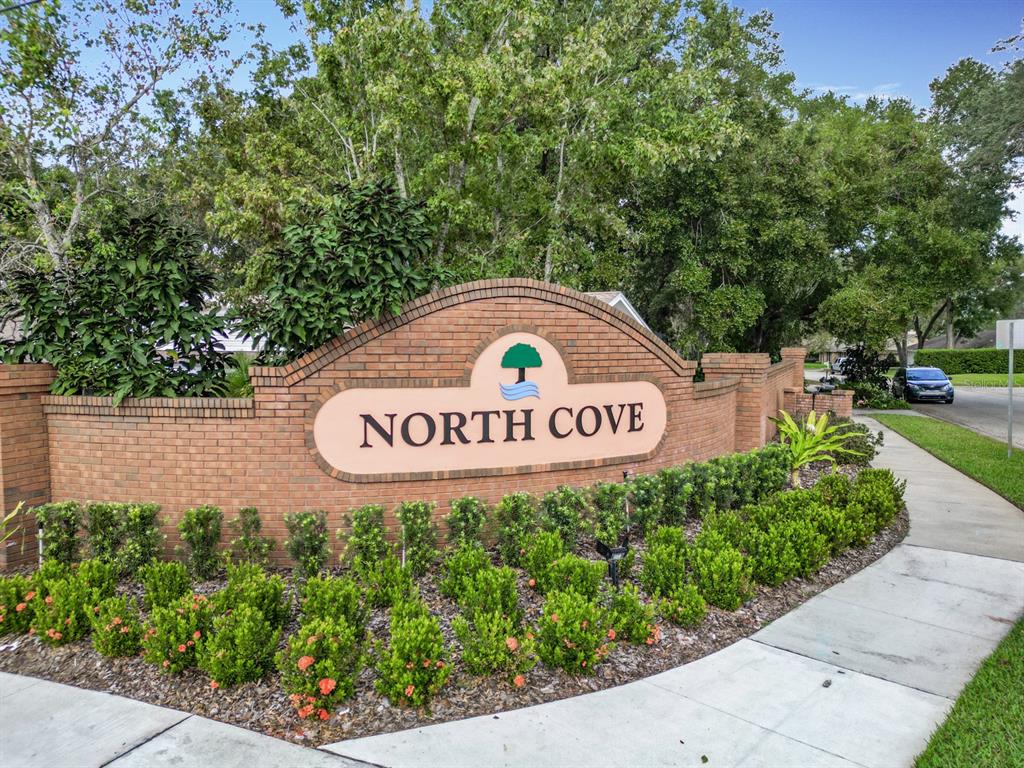 A brick monument sign for North Cove stands in a landscaped area near a sidewalk — 1469 GRACE LAKE CIRCLE, LONGWOOD, FL