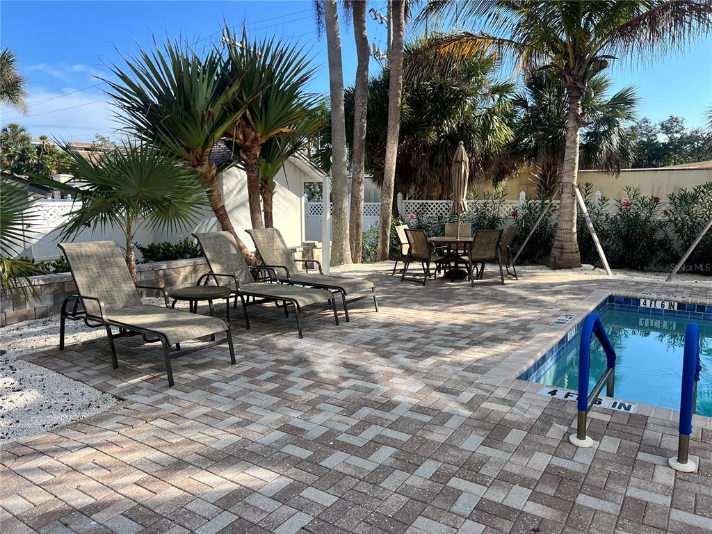 A paved pool deck features lounge chairs, a dining set, and palm trees — 1001 POINT OF ROCKS ROAD UNIT 308, SARASOTA, FL
