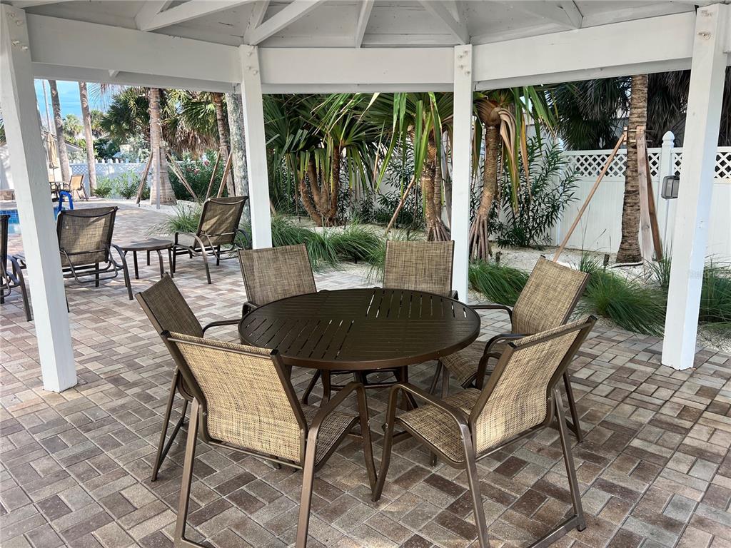 A round outdoor dining table with six chairs sits under a white wooden gazebo — 1001 POINT OF ROCKS ROAD UNIT 308, SARASOTA, FL