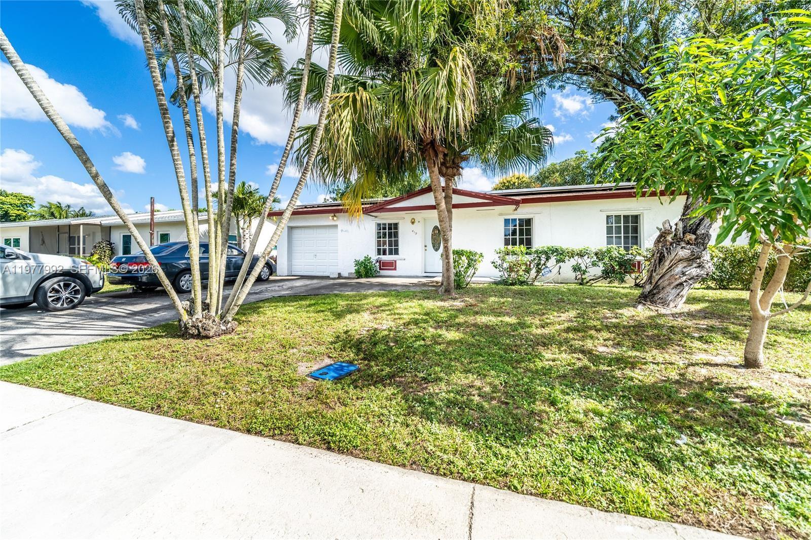 A single-story white house with a garage and palm trees sits behind a front lawn — 419 SW 80th Ave, Pompano Beach FL 33068, POMPANO BEACH, FL